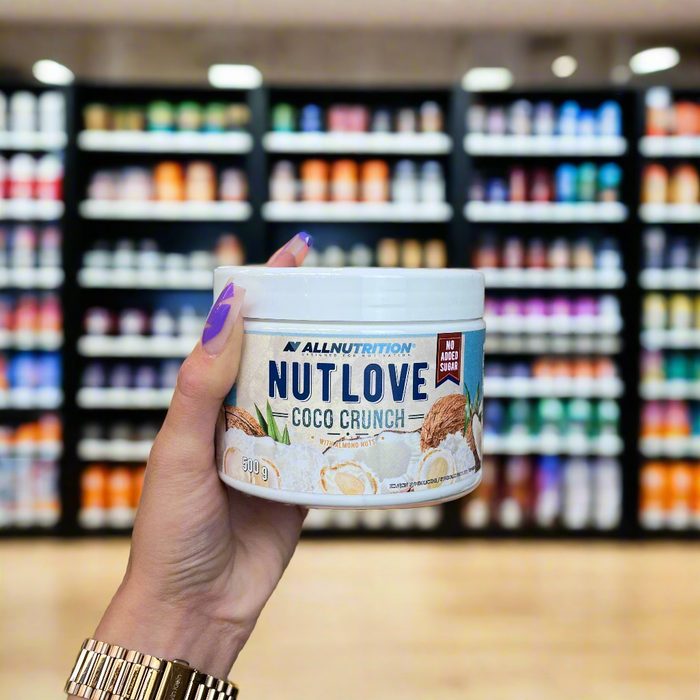 Close-up of (Allnutrition Nutlove Coco Crunch 500g) held up inside My Supplement Shop, clearly showing the front label in a Sports Nutrition setting.